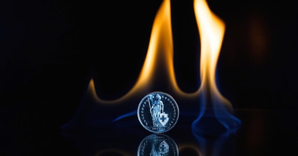 A coin stands against dramatic flames with a reflective surface, showcasing fiery abstract art.