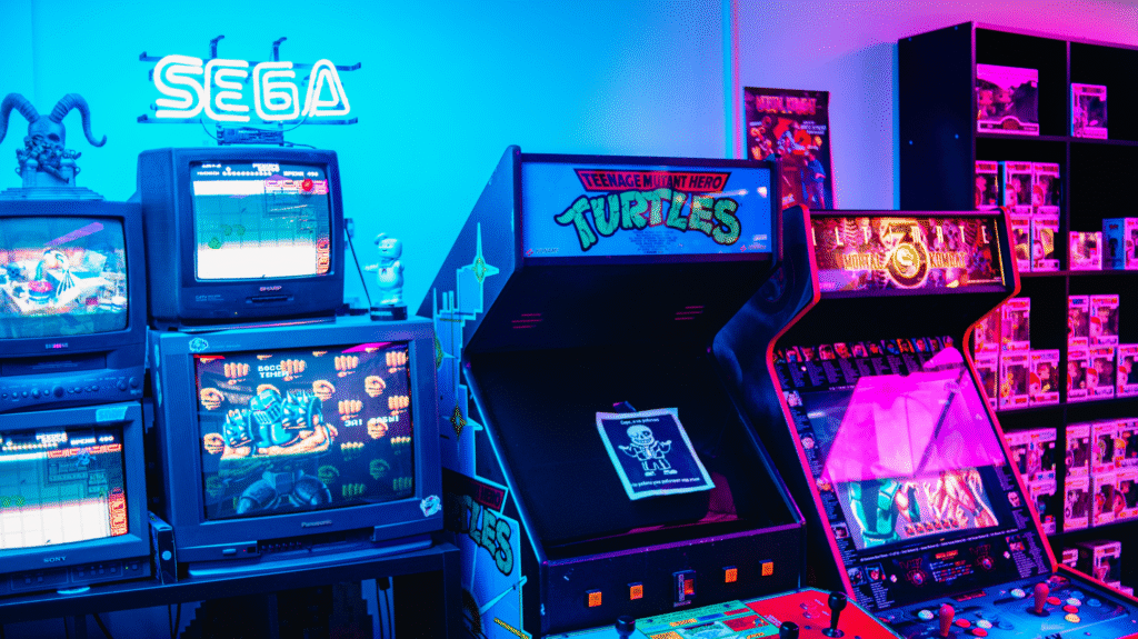 Retro arcade gaming setup with SEGA sign, Teenage Mutant Hero Turtles and Mortal Kombat machines, surrounded by vintage TVs and collectibles