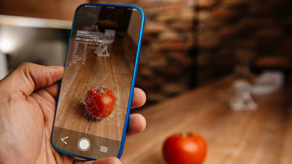 Hand holding a smartphone showing an augmented reality (AR) interface analyzing a tomato with nutritional information overlayed on screen